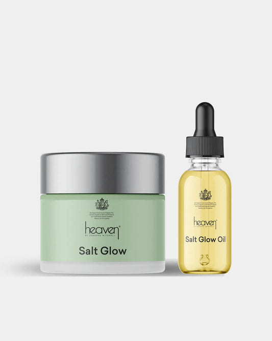 Green jar of salt glow scrub and yellow bottle of salt glow oil on a light gray background
